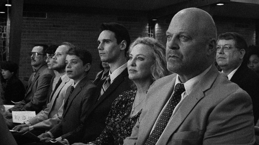 A black and white still of Michael Chiklis, Virginia Madsen, Cory Michael Smith and Aidan Langford sitting together in 1985.