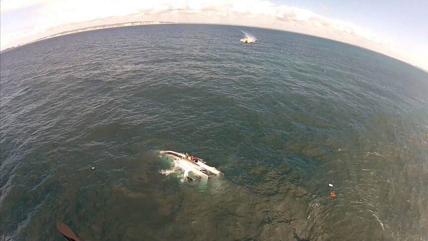 The rescue helicopter approaches the capsized boat off Queensland's Fraser coast today.