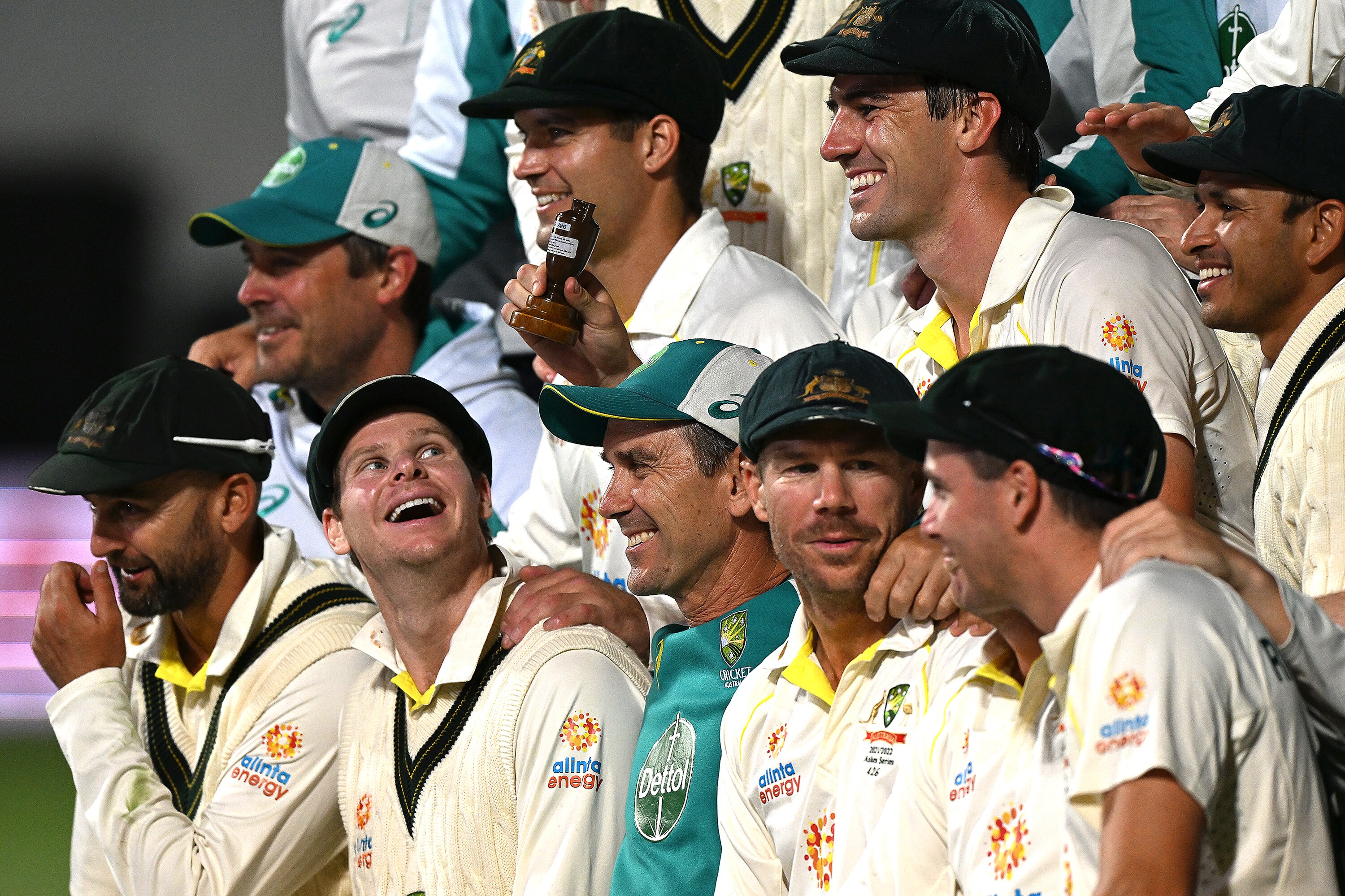 A group of Australian cricketers chat and laugh in the middle of a photo session after their win in the Ashes series.