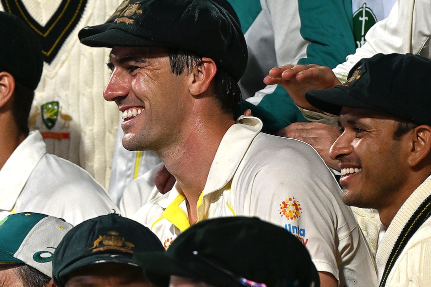 A group of Australian cricketers chat and laugh in the middle of a photo session after their win in the Ashes series.