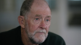 An older man with close-cropped hair and a neat beard, wearing black.