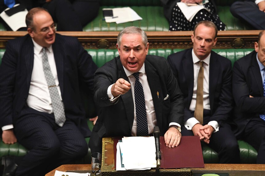 Britain's General Attorney Geoffrey Cox speaks in Parliament, he appears heated and is pointing his finger.