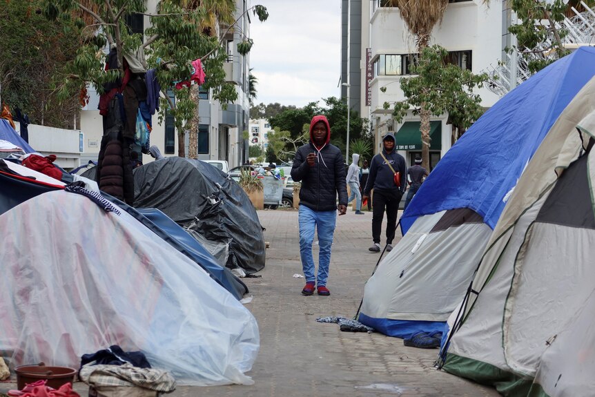 A man walks down a road where tents have been erected either side