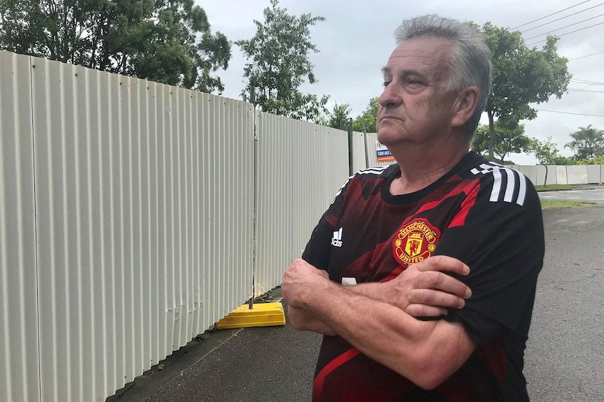 David Lambert stands at the temporary fence next to his unit in Wooraka Street at Rochedale South, south of Brisbane.
