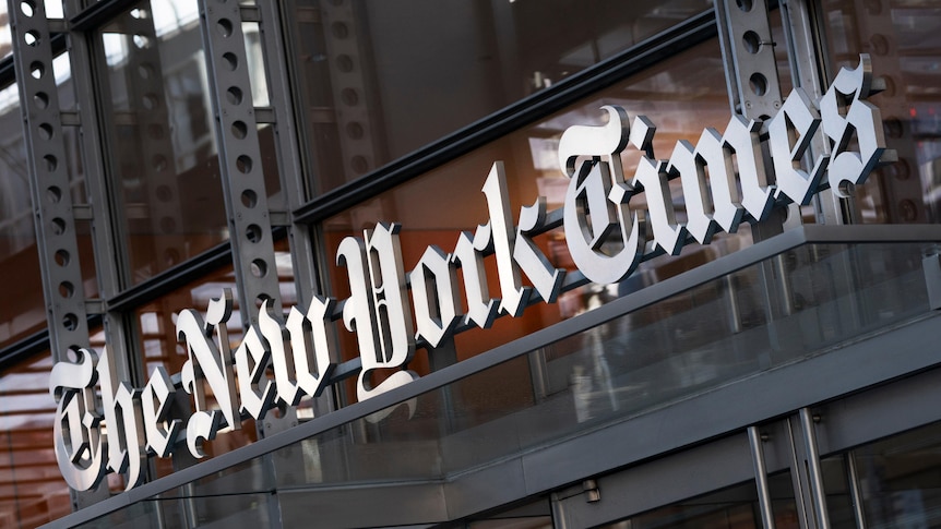 Signage on a glass fronted building reads 'The New York Times' in a calligraphic font