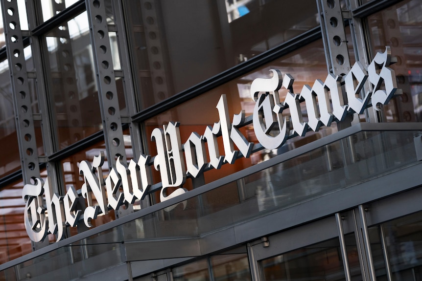 Signage on a glass fronted building reads 'The New York Times' in a calligraphic font