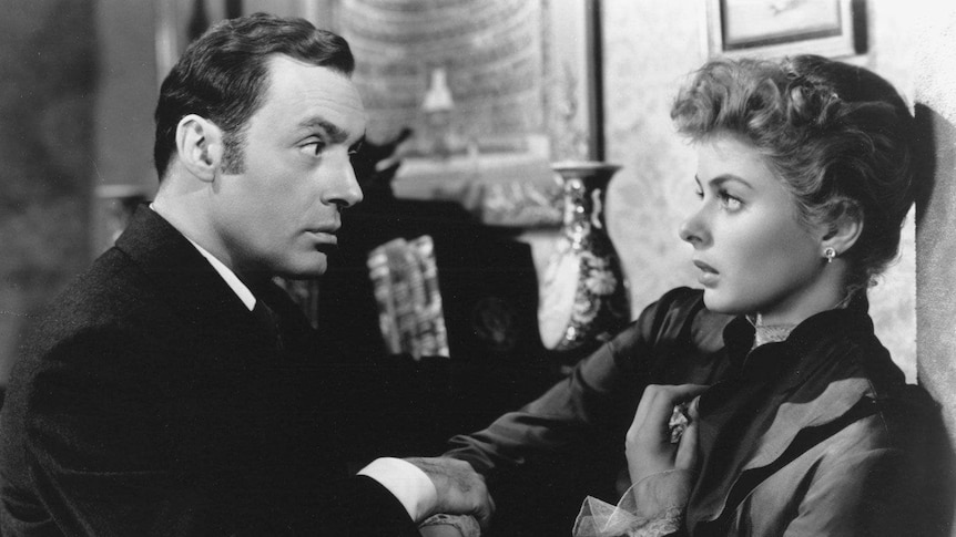 A black and white still from the film "Gaslight" where Charles Boyer and Ingrid Bergman are facing each other.