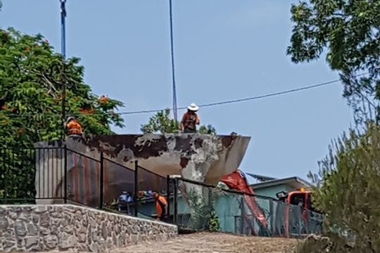 Workers operating crane over sculpture