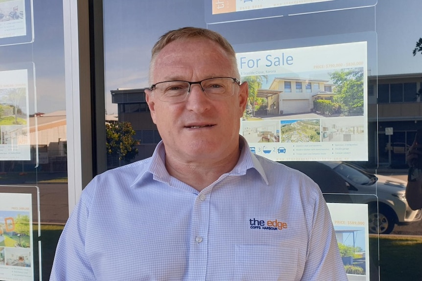 Real estate agent in front of his window advertisements