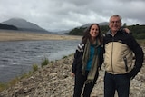 Katie Lees and her father Ian stand with their arms around each other and smiling in front of a lake.