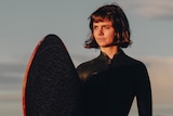 woman standing on a beach with a surfboard