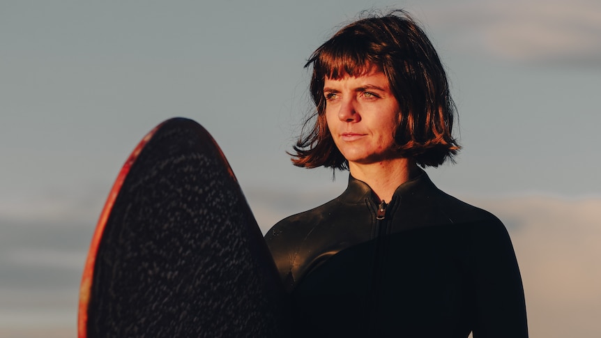 woman standing on a beach with a surfboard