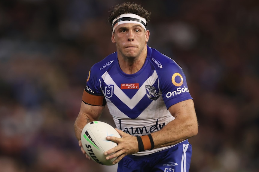 A Canterbury NRL player runs with the ball in two hands during a match in 2021.