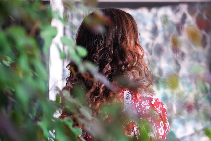 Leaves in foreground woman with curly hair looks away from the camera