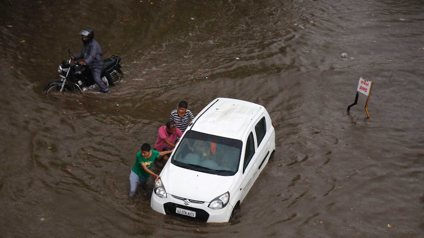 Men push a car submerged in India during floods