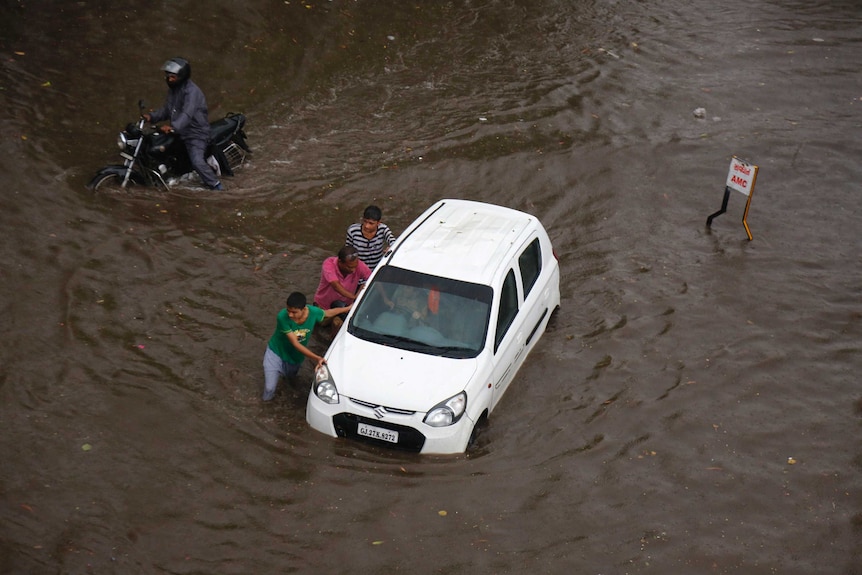 Men push a car submerged in India during floods
