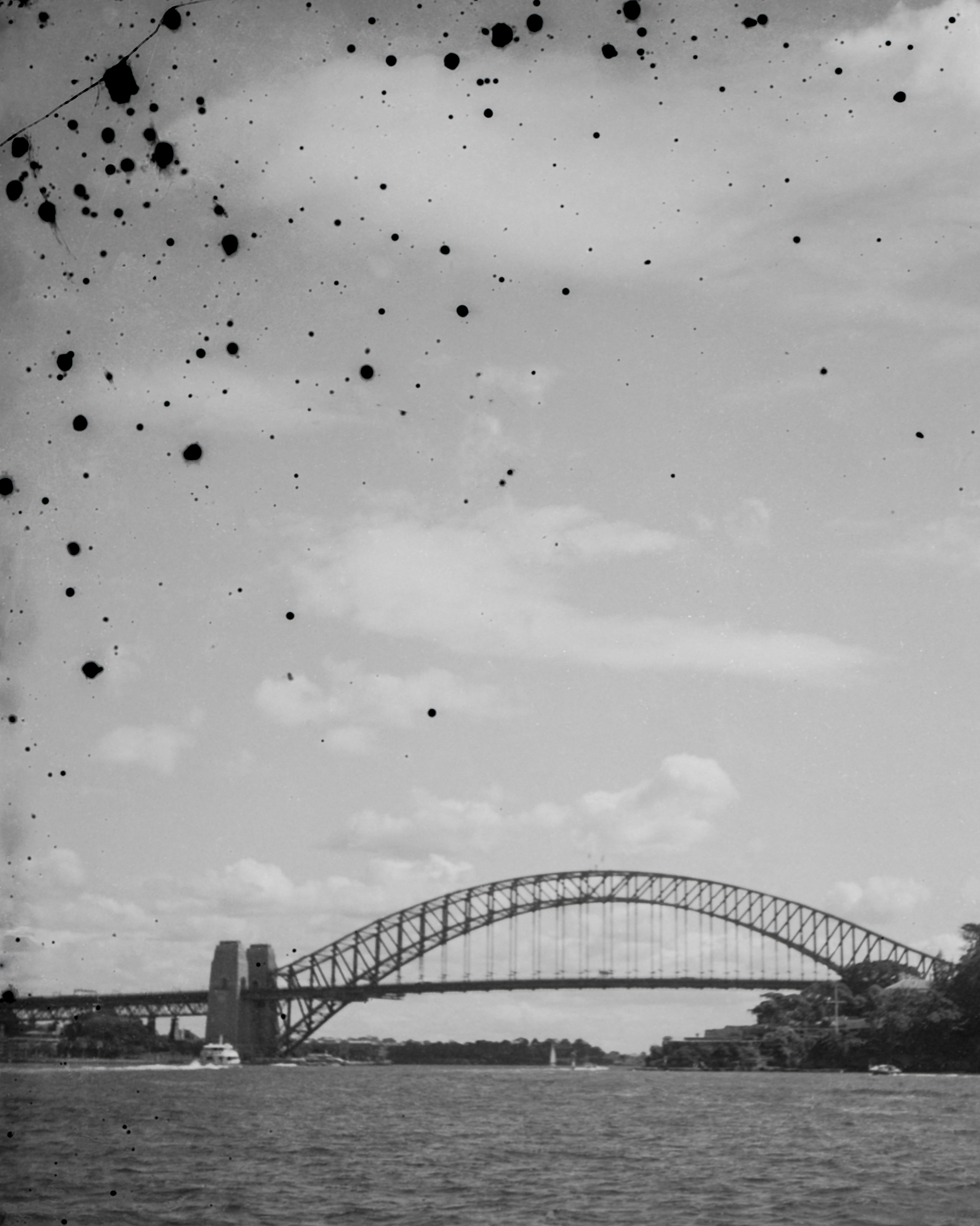 Artwork by Sammy Hawker, of a film photo of the Sydney Harbour bridge with dots of erosion marks on the image