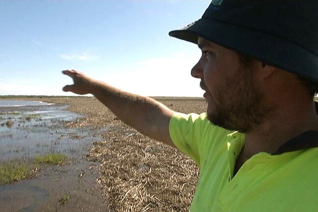 Man points to flooded farmland