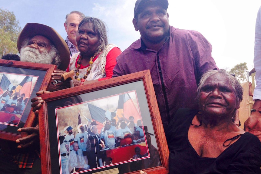 Aboriginal elders hold photos from the 1985 handover of Uluru at the 30th anniversary of the handover