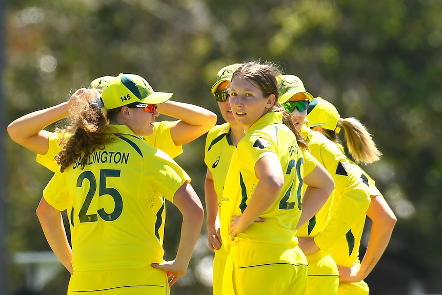 Darcie Brown looks back over her shoulder, surrounded by teammates in yellow shirts