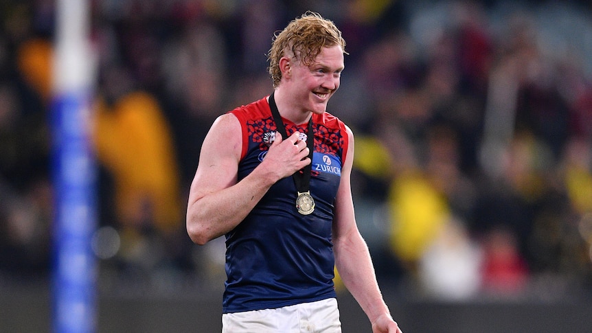 Clayton Oliver of the Demons smiles with a medal around his neck at the MCG.