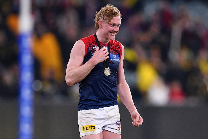 Clayton Oliver of the Demons smiles with a medal around his neck at the MCG.