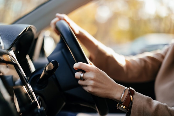 a womans hands on a steering wheel inside a car