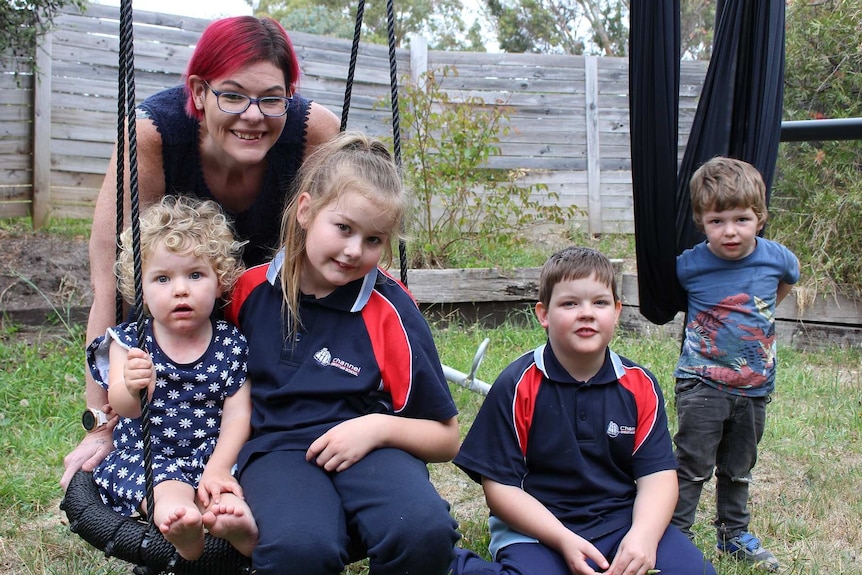 Tasmanian mum Cass Whitehill with her children on a backyard swingset.