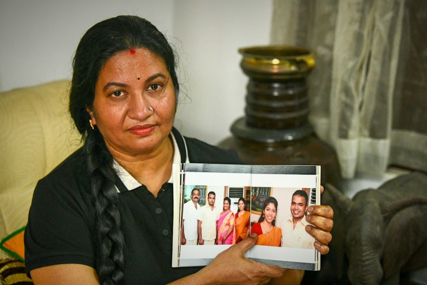 Bindu, an Indian woman with a thick long braid, holding photos of her daughter.