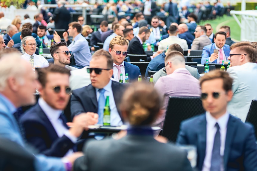 People sitting down at tables outside at a race in Randwick