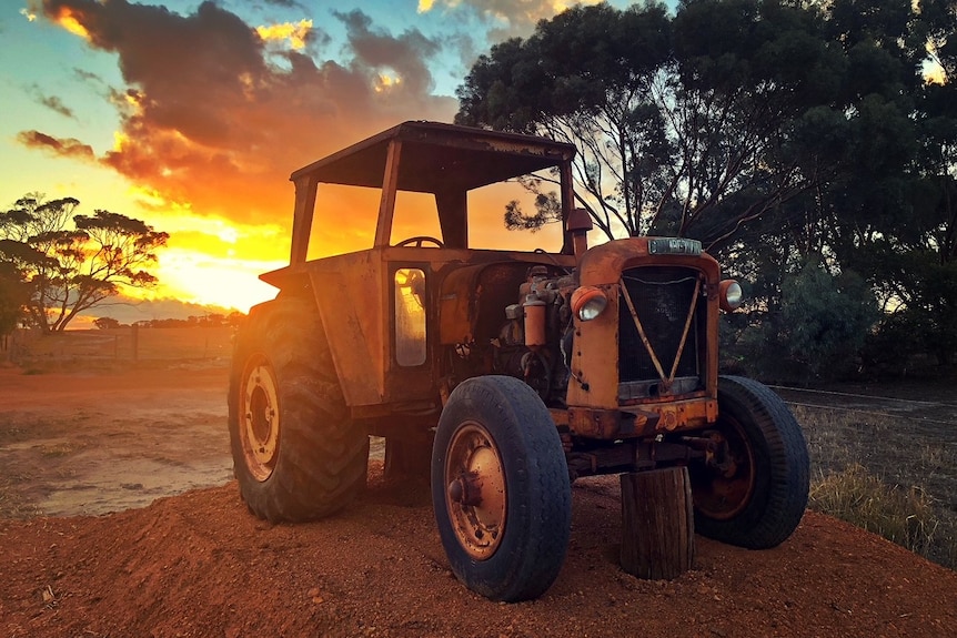 A tractor with the sunset behind it.