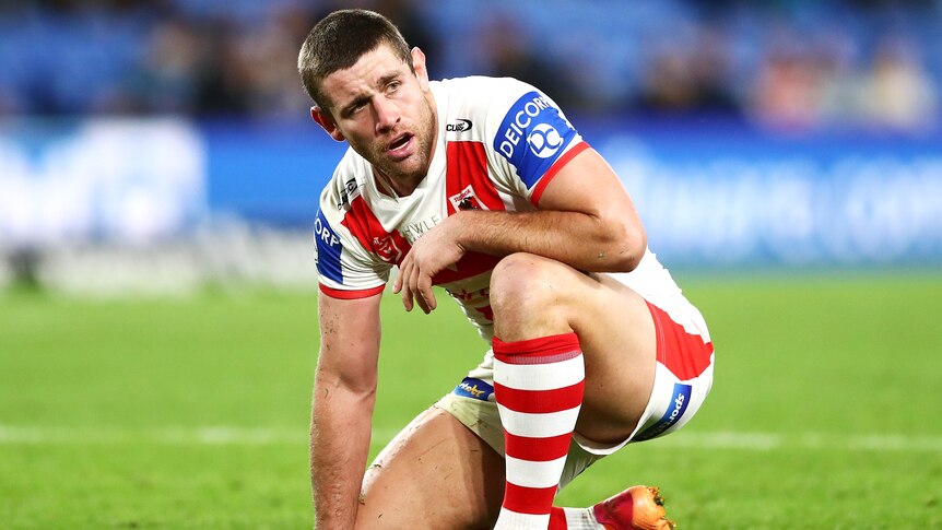 A St George Illawarra NRL player kneels during a match as he gathers his breath.