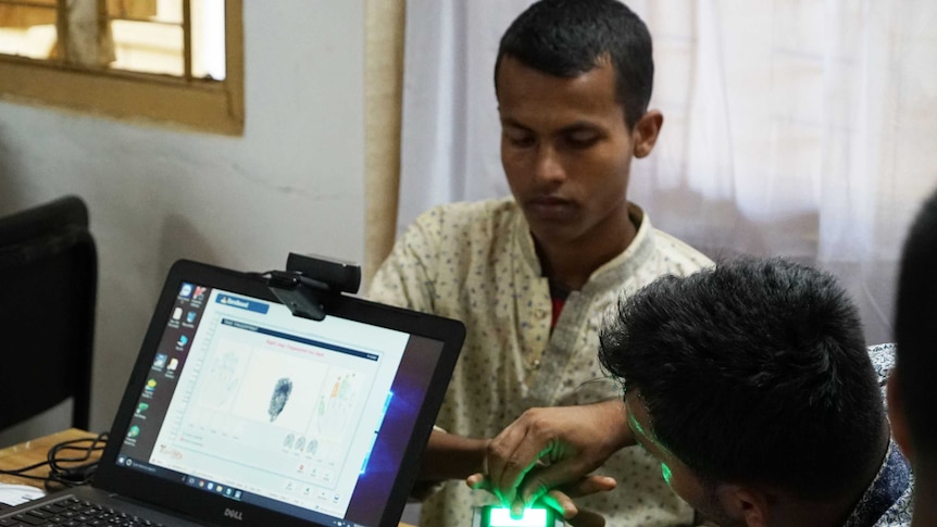A Rohingya man has fingerprint scanned, with his print visible on a computer screen.