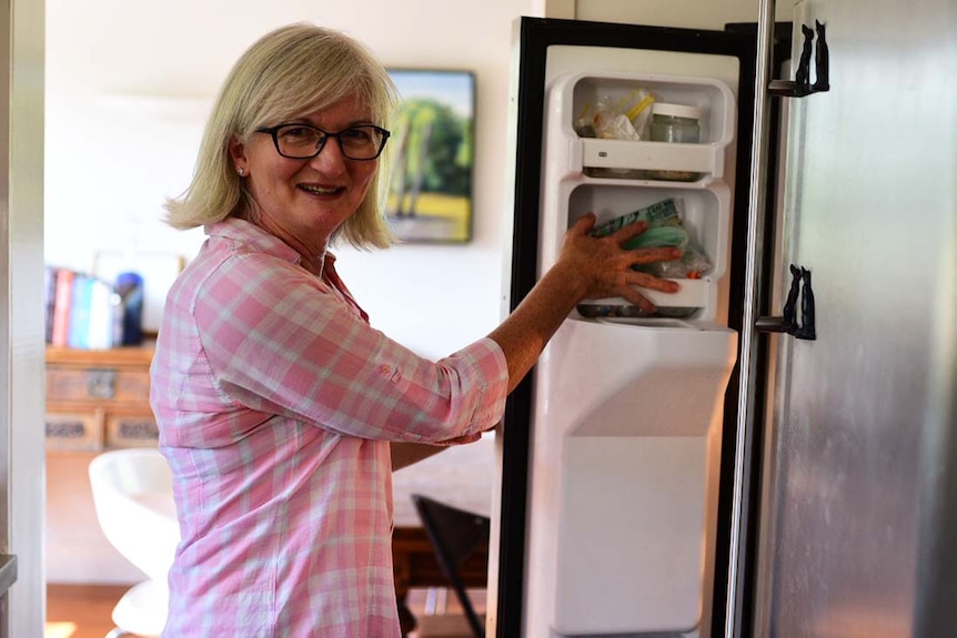Brisbane resident Jennifer Nielsen reaches for food in her fridge in her home.