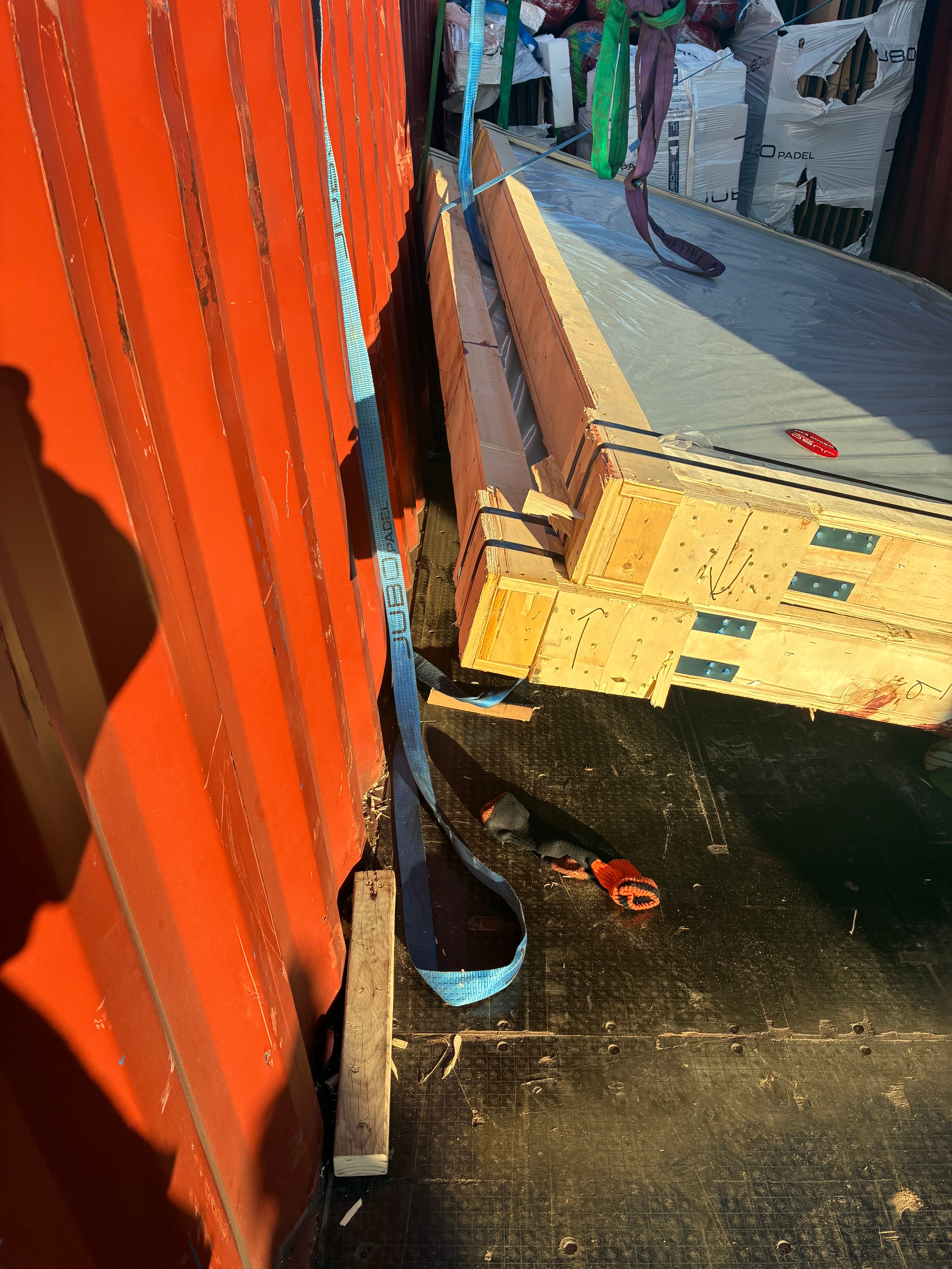 Two packets of glass frames resting on the ground while attached to straps, some weight still being taken by the straps