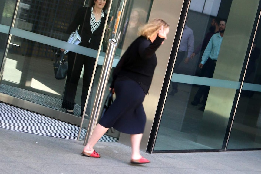 Rachel Buckeridge making an obscene finger gesture as she exits a revolving door.