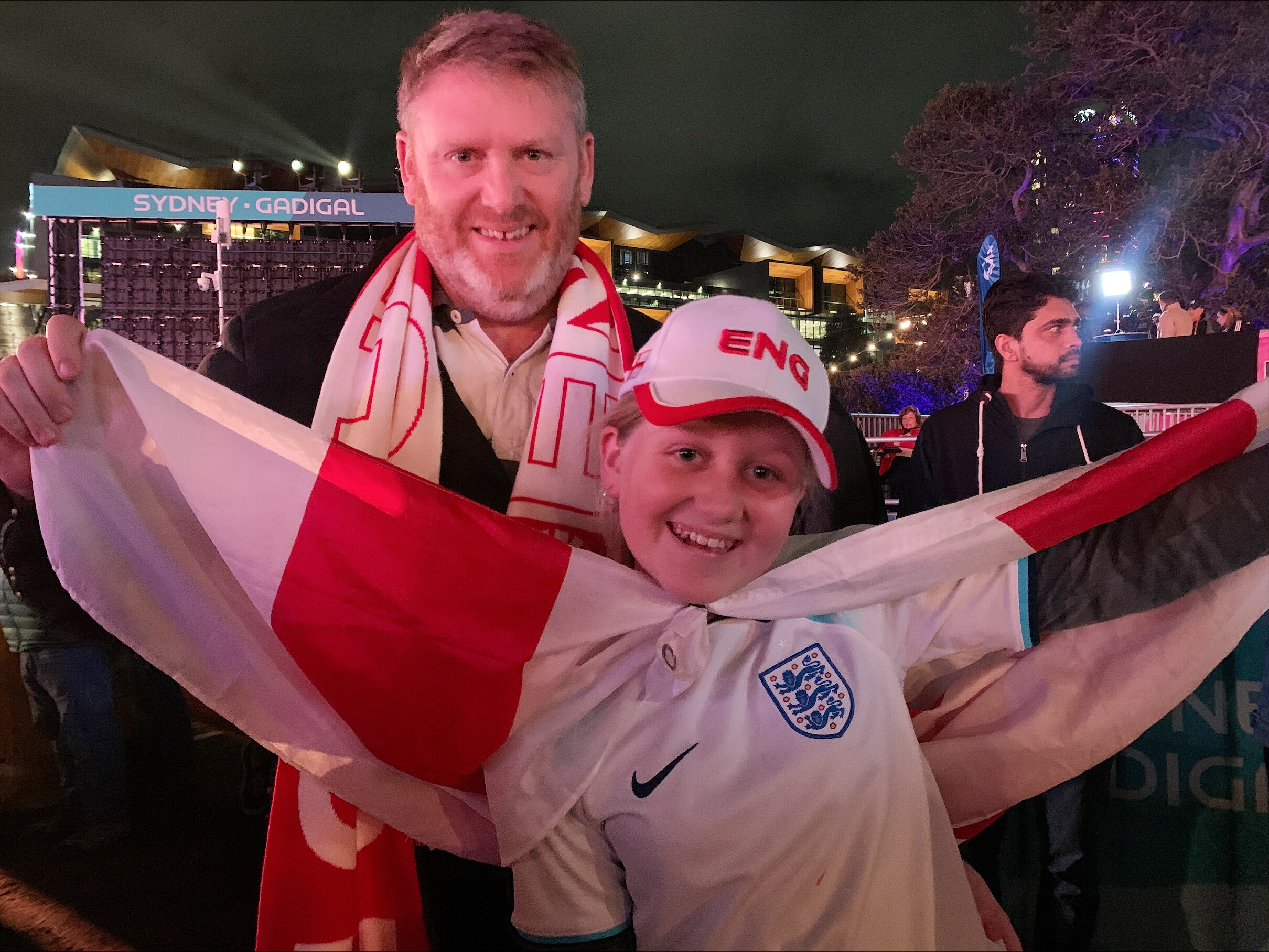 a man and a young girl carry a danish flag as they watch a football game