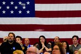 Sympathisers, standing in front of an American flag react as they attend a campaign event of Pete Buttigieg