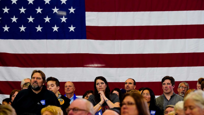 Sympathisers, standing in front of an American flag react as they attend a campaign event of Pete Buttigieg