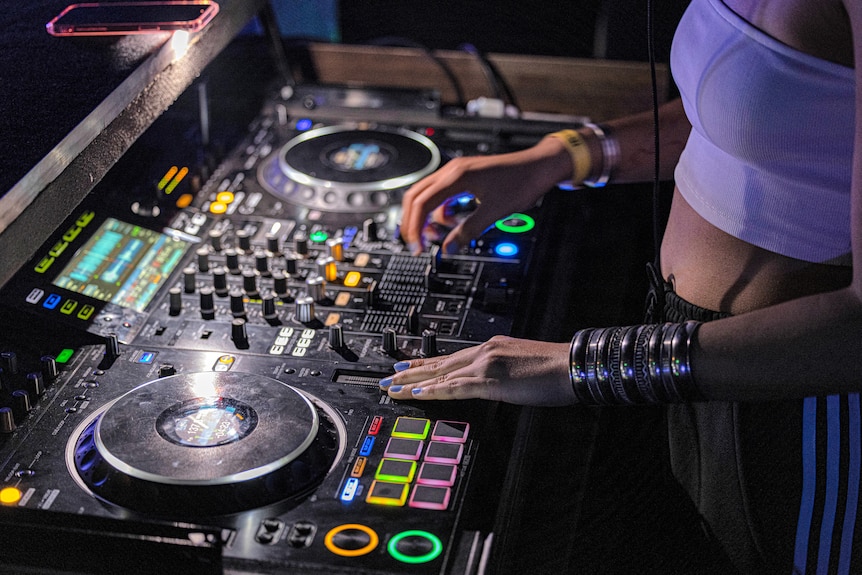 a close up of a DJ console with a woman's hands shown working on the console
