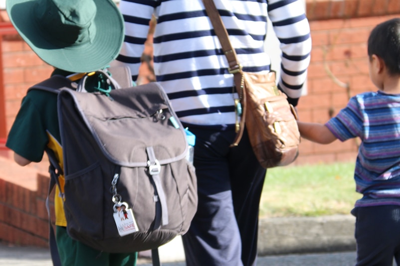 Unidentified young students walking to school with parent.