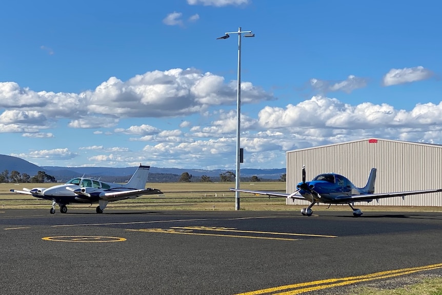 Two light aircraft on a regional airport runway.