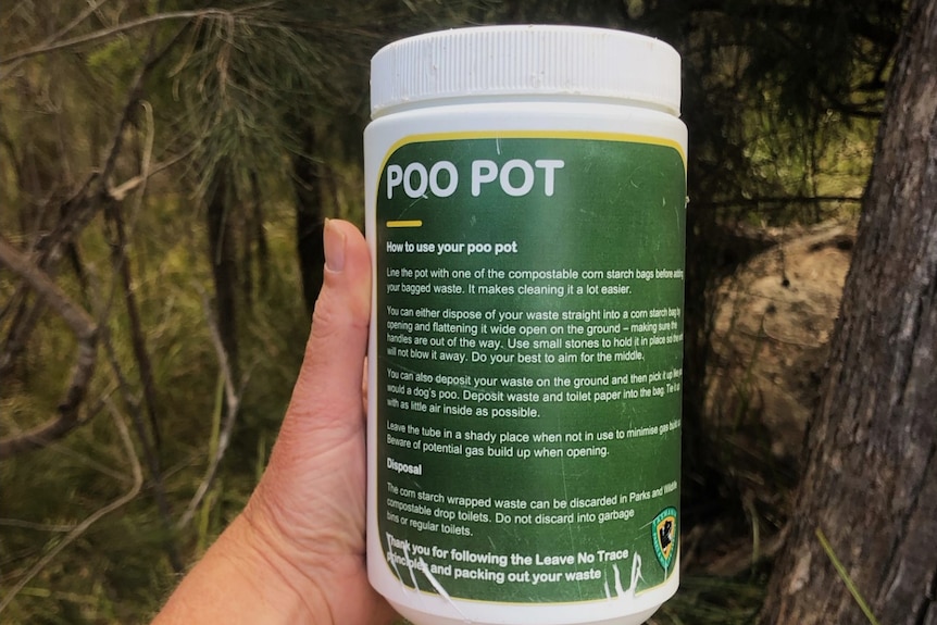 A hand holding a green and white container labelled poo pot.