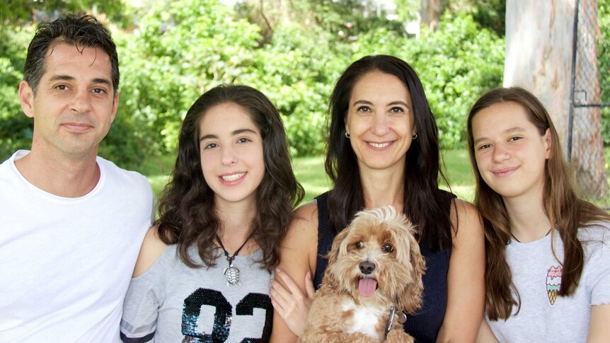 Andrea Zorbalas holding a dog and with her two daughters and husband