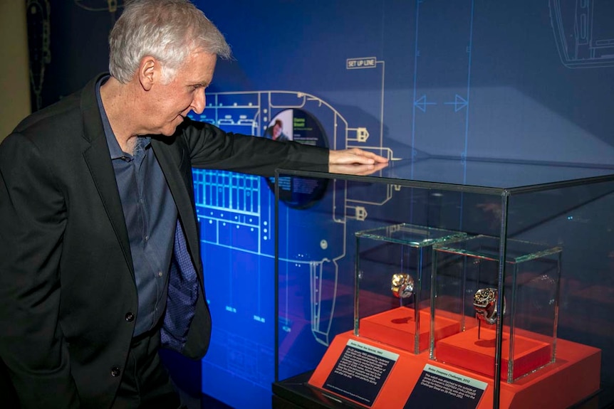 James Cameron looks at two watches in cabinets as part of the Challenging the Deep exhibition.