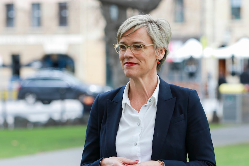 Jen Butler con gafas, blazer azul marino y camisa blanca, con Salamanca al fondo.