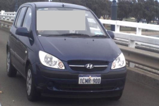 A photo of a blue Hyundai Getz driving on the road, taken from in front of the vehicle.