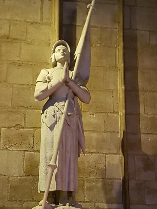 A statue of a person praying inside Notre Dame cathedral.