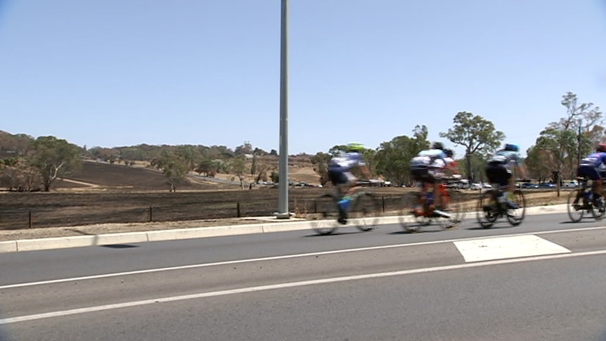 Cyclists riding past burnt ground