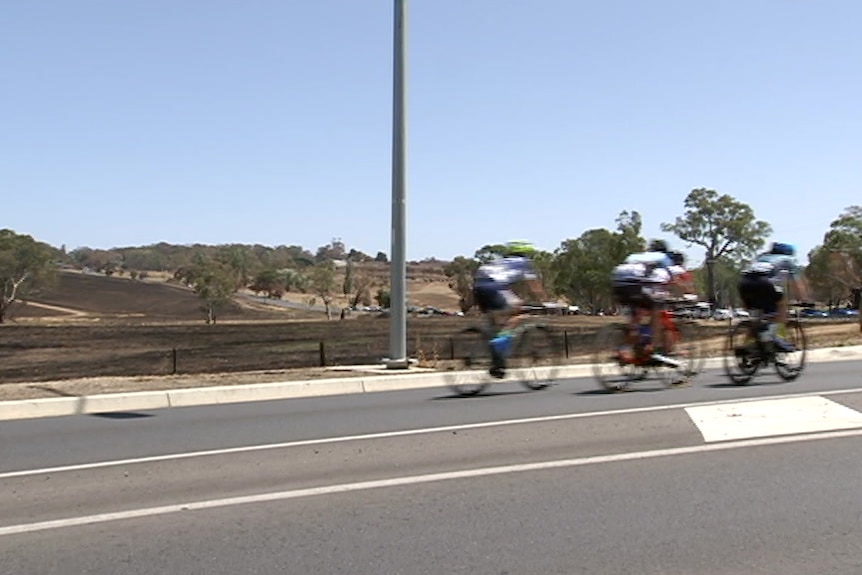 Cyclists riding past burnt ground